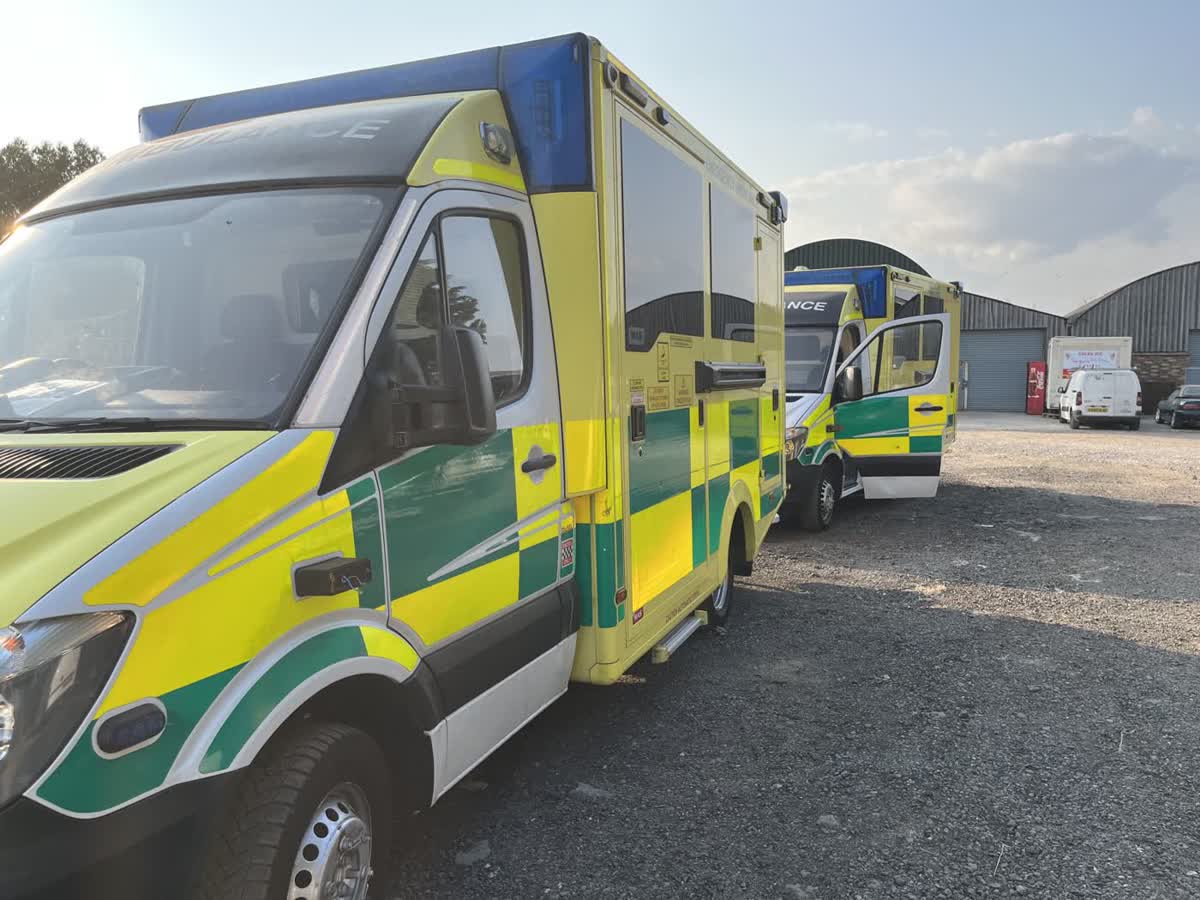 Two ambulances parked on gravel outside the farm buildings, held back with mechanical issues