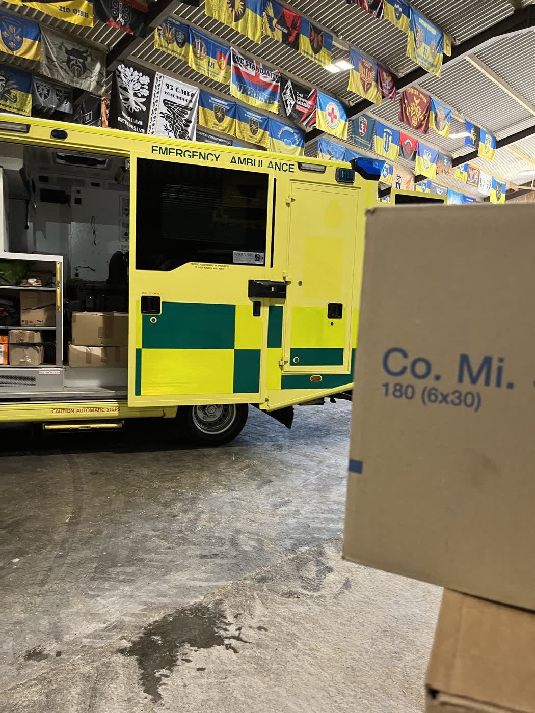 An ambulance inside the barn with its side door open being loaded with boxes of aid