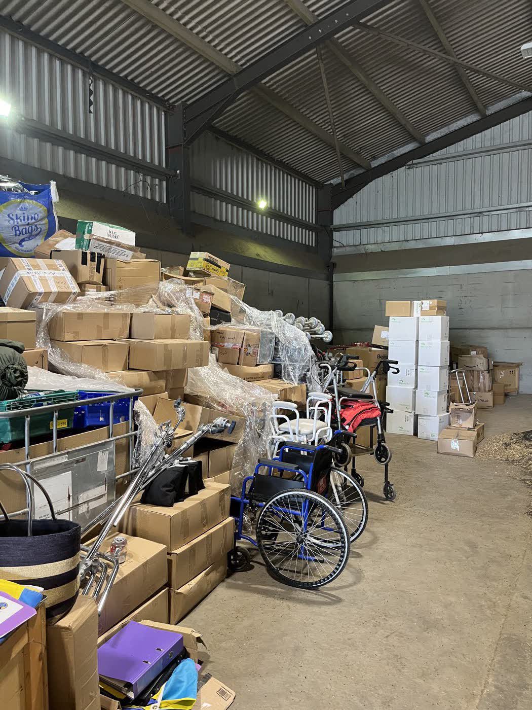 A farm barn stacked to the roof with boxes of aid, wheelchairs, walking frames and shower chairs waiting to be loaded