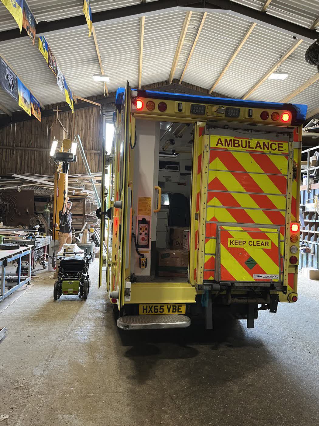 The rear of an ambulance inside the barn with its tail doors open during loading