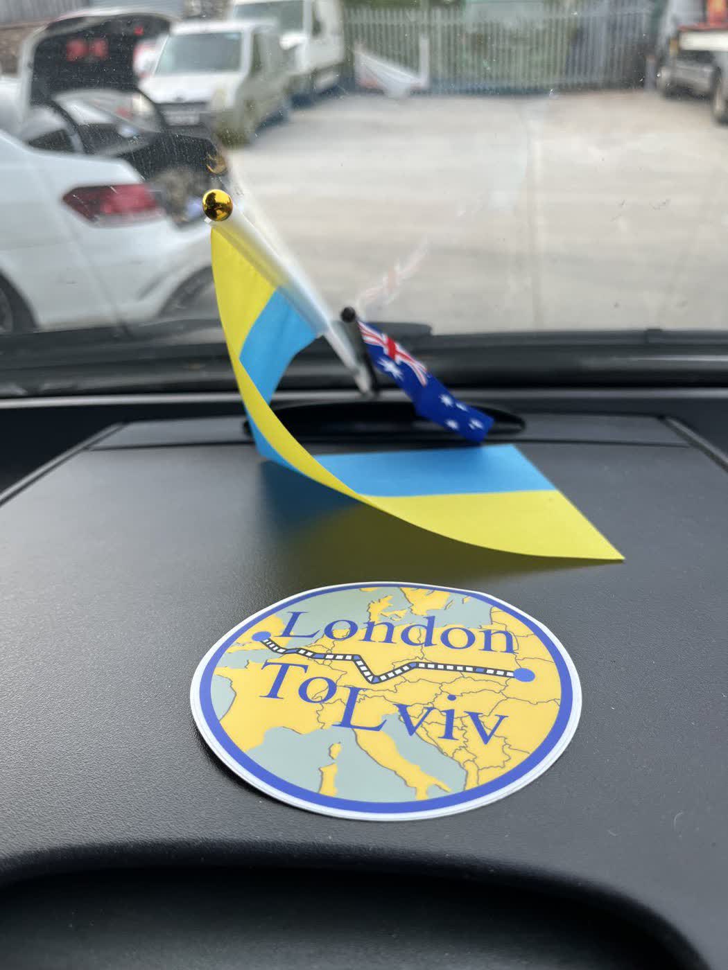 A dashboard with a Ukrainian flag, an Australian flag and a round London to Lviv route badge showing the drive across Europe