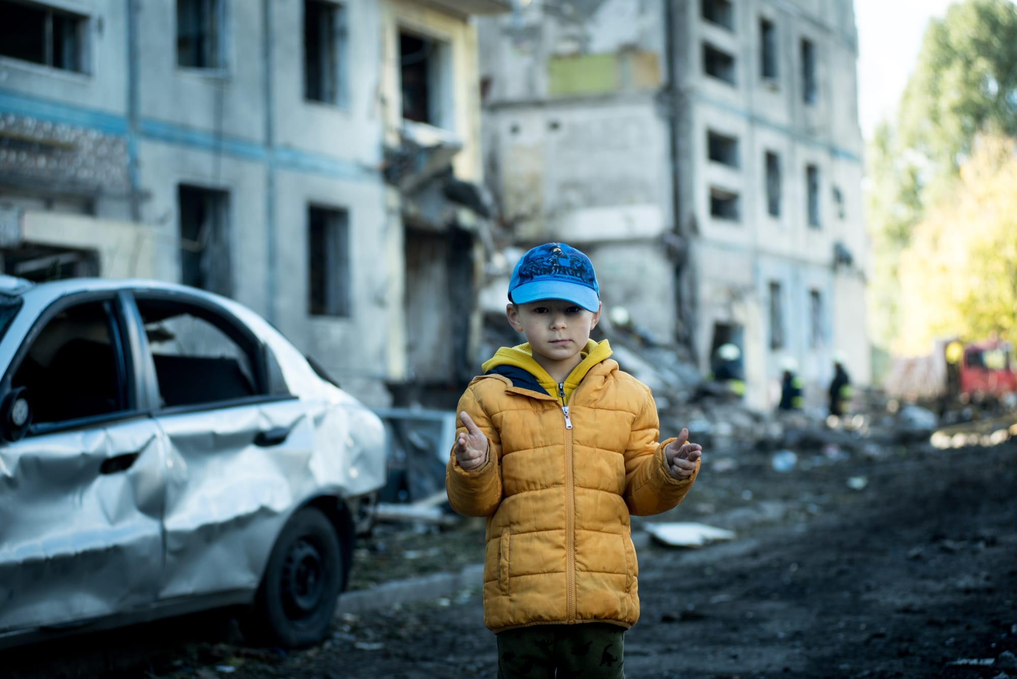 Ukrainian child standing before a bombed building - Medaria Aid supports orphans and displaced children